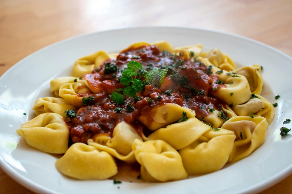 Close-up of tortellini with rich tomato basil sauce on a white plate.