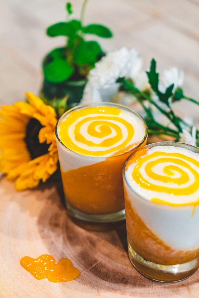 Delicious homemade mango yogurt with spiral design in a glass, styled with sunflowers.