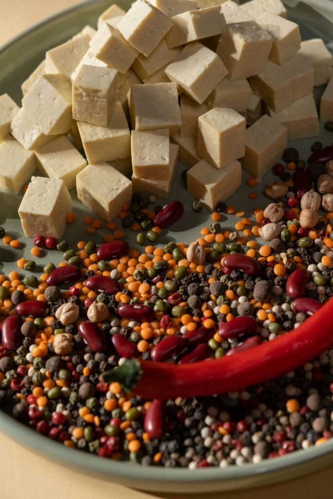 Close-up of tofu cubes, chili pepper, and colorful beans on a plate.